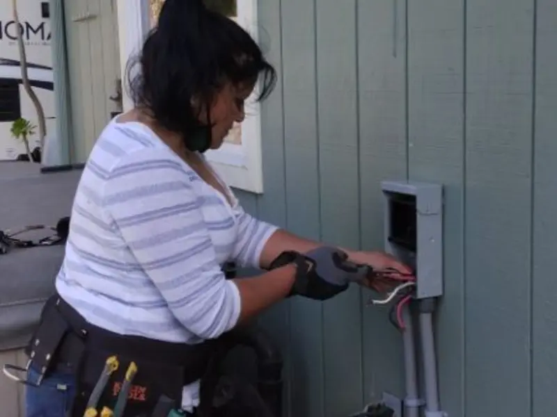 Licensed electrician wiring an exterior subpanel in Tangerine